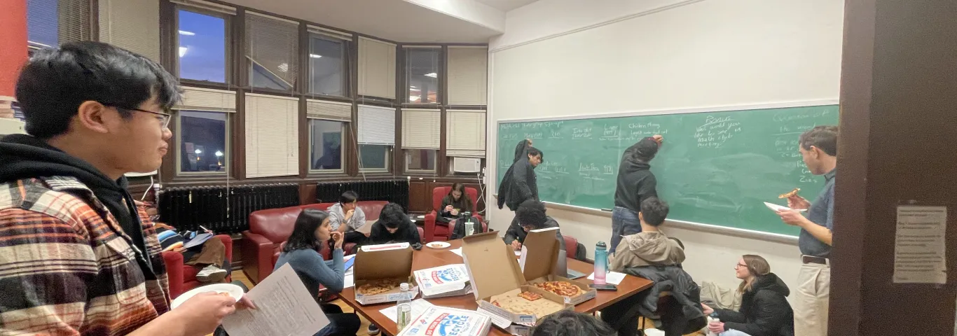 Students eat pizza, write on a chalk board, and have mathematical discussion