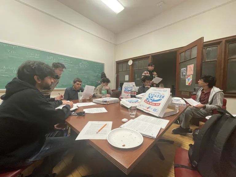 Students eat pizza, write on a chalk board, and have mathematical discussion